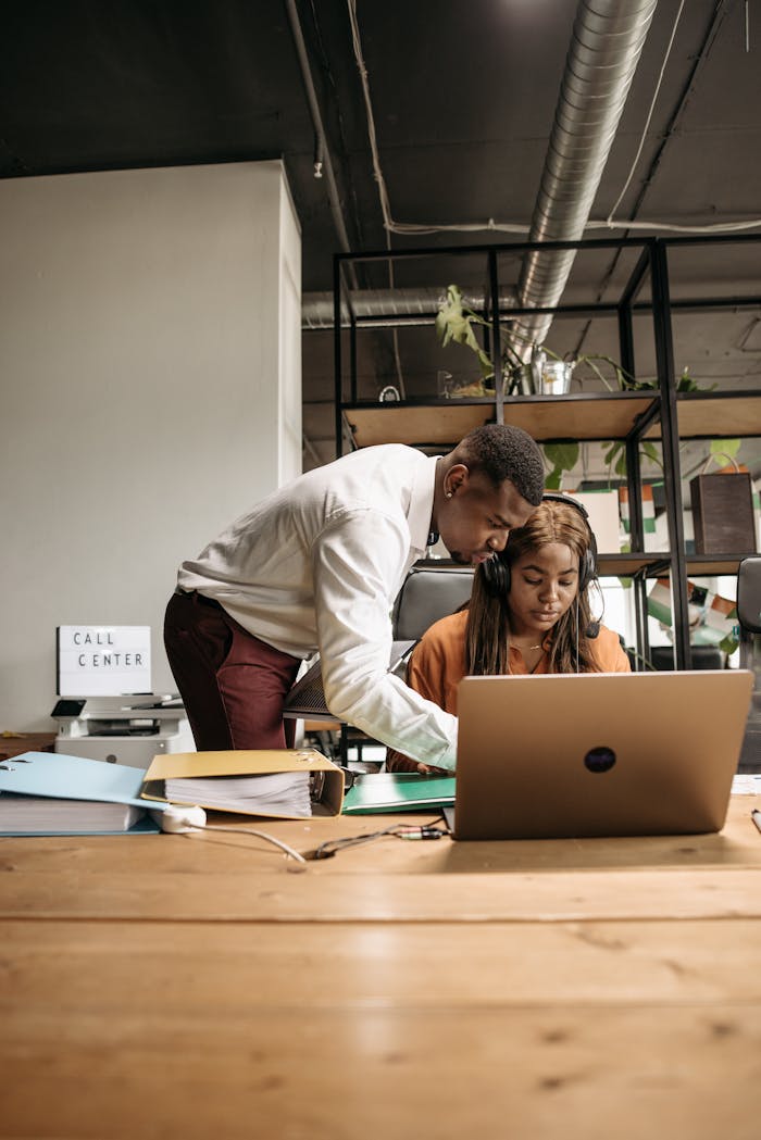 Two call center employees collaborating and working with a laptop.